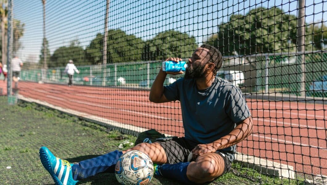 Amateurvoetballer tankt bij langs het veld na de training