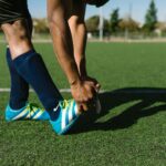 Voetballer rekt zijn knie en pees uit tijdens de warming-up op het veld