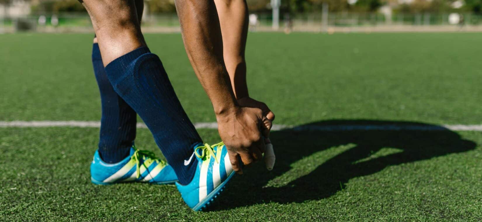 Voetballer rekt zijn knie en pees uit tijdens de warming-up op het veld