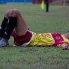 Vermoeide voetballer zit uitgeput op het veld na een intensieve wedstrijd