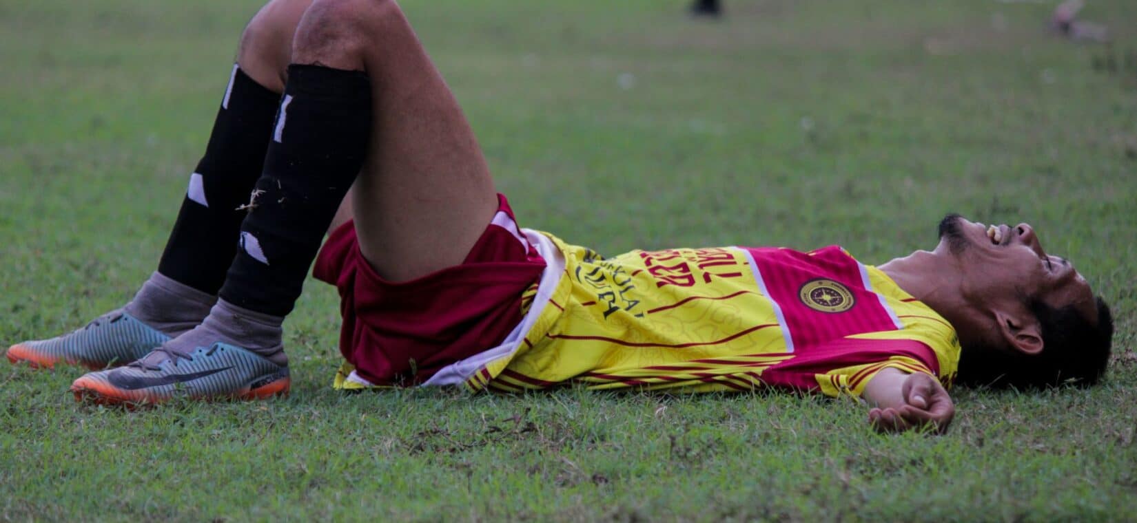 Vermoeide voetballer zit uitgeput op het veld na een intensieve wedstrijd