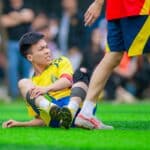 Voetballer grijpt naar zijn knie na een blessuremoment tijdens een wedstrijd