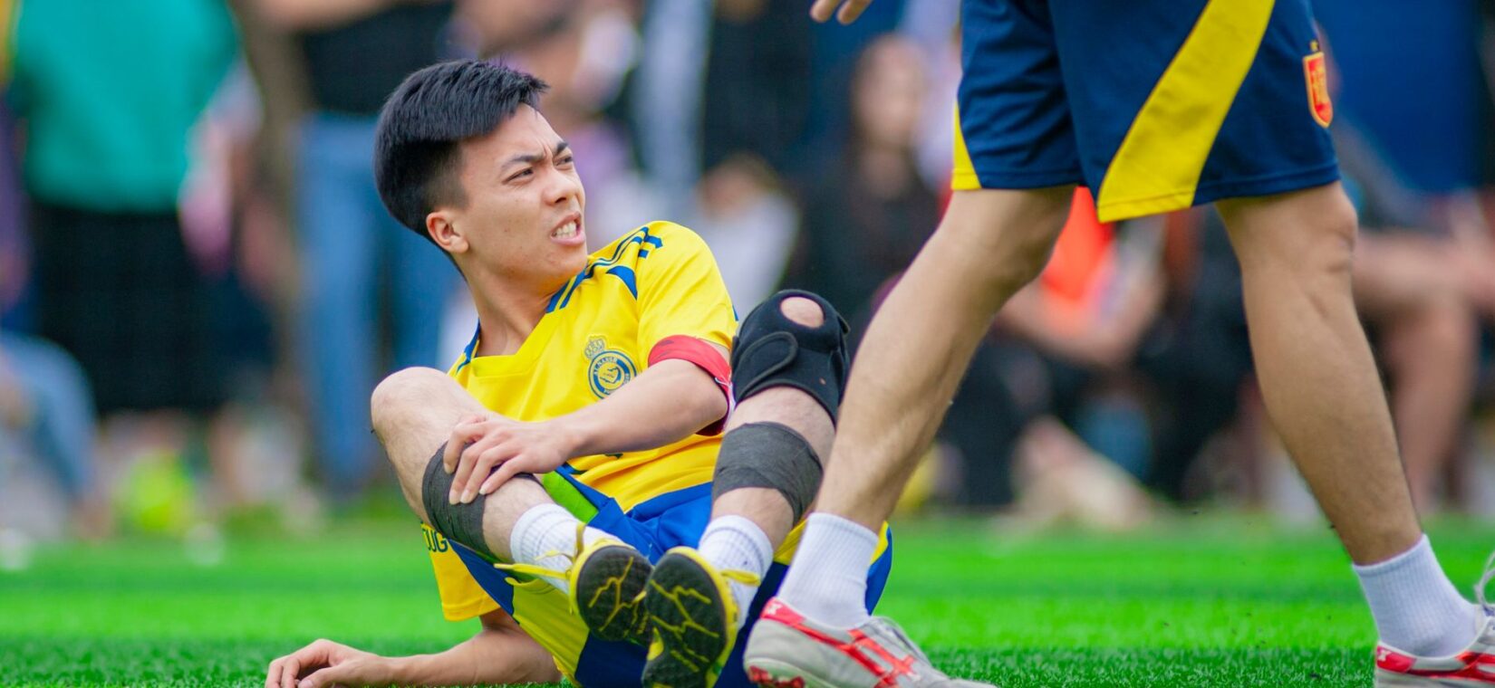 Voetballer grijpt naar zijn knie na een blessuremoment tijdens een wedstrijd
