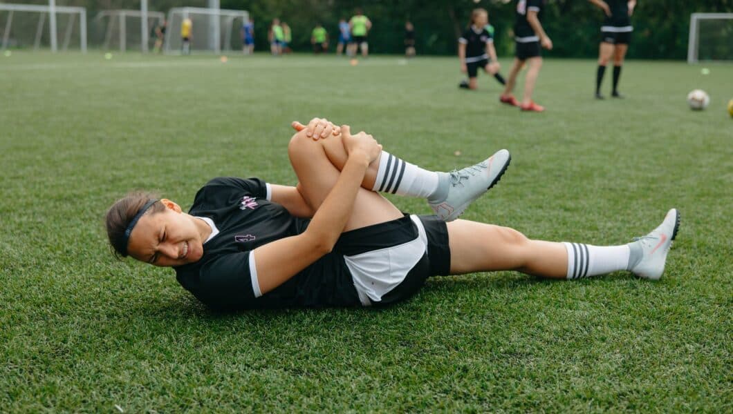 Voetballer grijpt naar de achterkant van zijn bovenbeen tijdens een wedstrijd