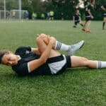 Voetballer grijpt naar de achterkant van zijn bovenbeen tijdens een wedstrijd