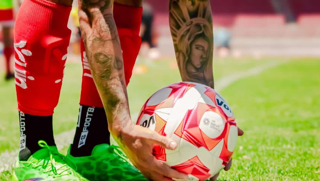 Voetballer gebruikt een foam roller op zijn bovenbeen na een training